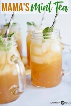 two mason jars filled with iced tea and mint garnish on top of a white table