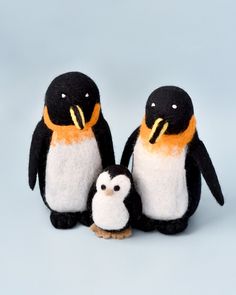 two stuffed penguins sitting next to each other on a blue background with an orange beak