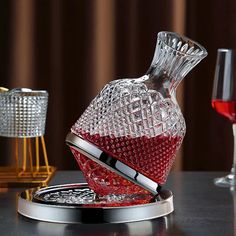 a glass decanter with red liquid in it sitting on a table next to two wine glasses