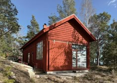 a small red house in the middle of some trees