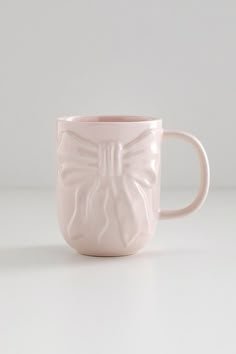 a pink coffee cup with a butterfly design on the outside and inside, sitting on a white surface