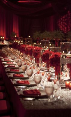 a long table is set up with red flowers and candles for an elegant dinner party