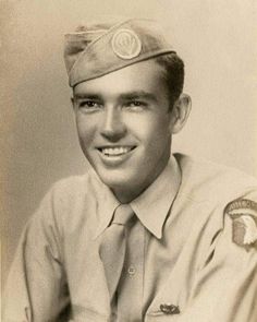 an old black and white photo of a young man in uniform smiling for the camera