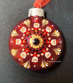 a red ornament hanging from a red ribbon on top of a black table