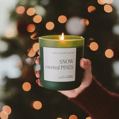 a person holding a candle in front of a christmas tree