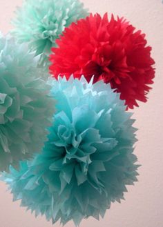 three red, blue and green paper pom - poms hanging from a ceiling