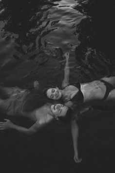 black and white photo of two people in the water, one laying on his back