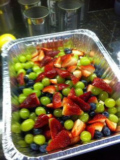 grapes, strawberries and green olives are in a plastic container on the counter