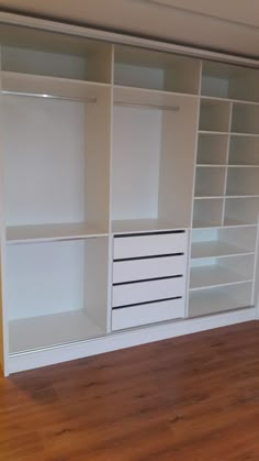 an empty room with white shelving and wooden floors