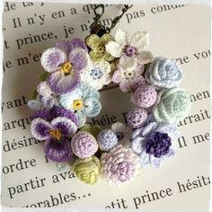 crocheted flowers are arranged in the shape of a wreath on top of an open book