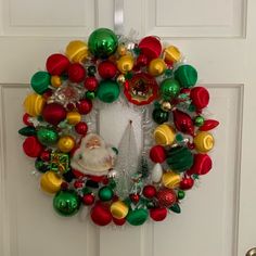 a christmas wreath is hanging on the front door with ornaments around it and santa clause