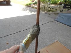 a person is holding a brush in front of a pole on the side of the road