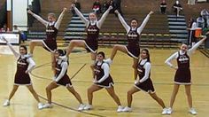 a group of cheerleaders in maroon and white outfits are dancing on a basketball court