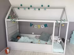 a small child is laying in his bed under the canopy with decorations around him and hanging from the ceiling