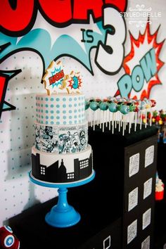 there is a cake and cupcakes on the table in front of the wall