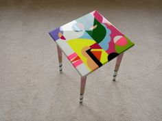 a multicolored stool sitting on top of a white carpet