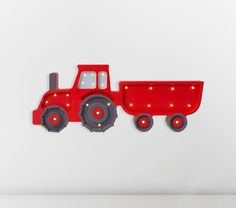 a red toy truck with lights on it's sides is hanging from the wall