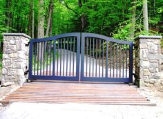 an iron gate with wooden steps leading into the woods