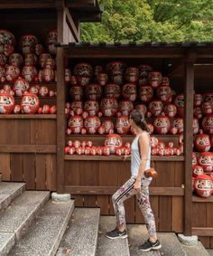 a woman walking down some steps in front of red vases