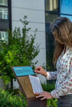 a woman standing in front of a building with a piece of paper on top of it