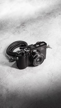 a black and white photo of a camera on the ground with a cord attached to it