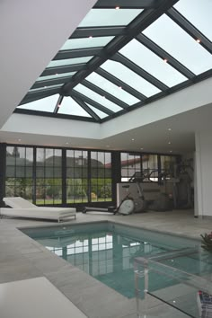 an indoor swimming pool with glass walls and skylights on the ceiling is shown in this modern home