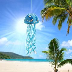 a blue jellyfish hanging from a palm tree on the beach