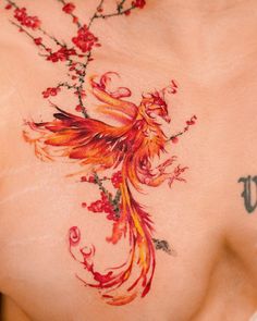 a woman with tattoos on her chest has a bird and flowers tattoo on it's chest