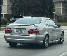 a silver mercedes cls is driving down the street in front of other cars and buildings