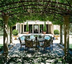 an outdoor dining area with tables and chairs under a pergolated trellis covered patio