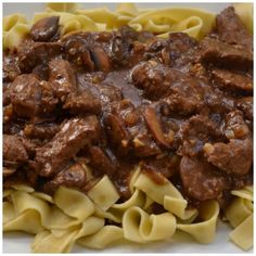 a white plate topped with pasta covered in beef and sauce on top of it's own