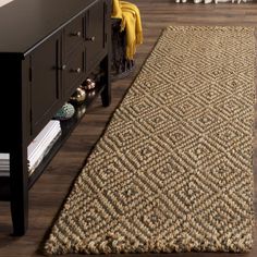 a living room with a rug on the floor next to a dresser and coffee table