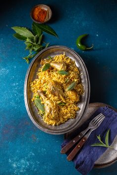 an overhead view of a plate of food on a blue surface with herbs and spices