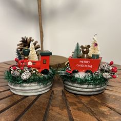 two christmas train figurines sitting on top of a wooden table