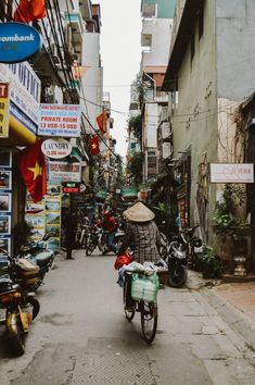 a person riding a bike down a street next to tall buildings and shops on both sides