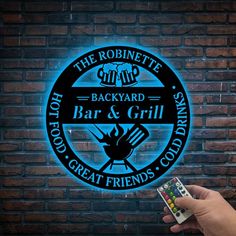 a person holding a remote control in front of a brick wall with a neon sign