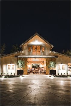 a large building with people sitting at tables in front of it and lights on the outside