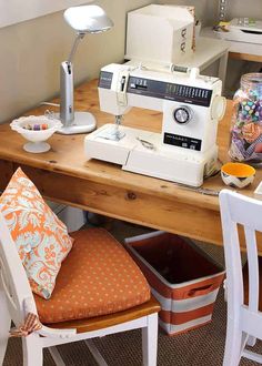 a sewing machine sitting on top of a wooden table next to a chair and lamp