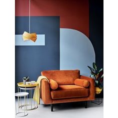 an orange chair in front of a blue and red wall with a lamp hanging from the ceiling