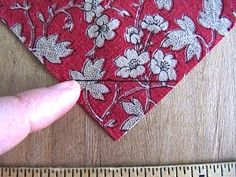 a person is measuring the length of a red flowered bandana with white flowers on it