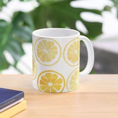 a yellow and white coffee mug sitting on top of a table next to a book