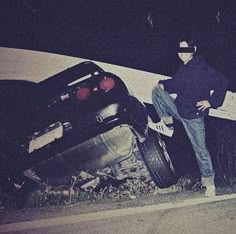 a man standing next to a wrecked car