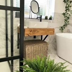 a bathroom with a sink, mirror and bathtub next to a plant in the corner