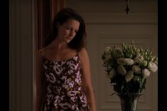 a woman standing in front of a vase with flowers