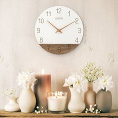 there is a clock on the wall next to vases and candles