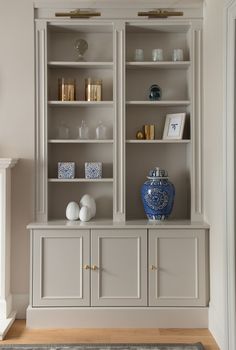 a white and blue vase sitting on top of a wooden shelf next to a wall