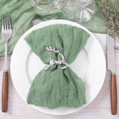 a white plate topped with a green napkin and silverware next to a fork and knife