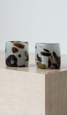 two white and brown cups sitting on top of a wooden table next to each other