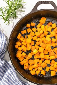 a skillet filled with cooked sweet potatoes on top of a blue and white towel