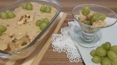 grapes and crackers in a glass dish on a wooden table next to a serving tray